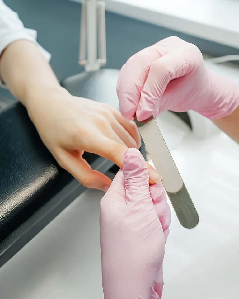 Manos con guantes realizando cuidado de uñas